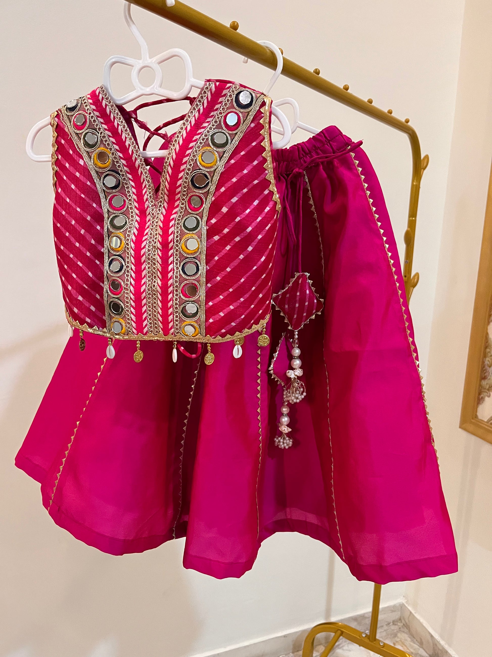 A bright magenta pink traditional lehenga/Chaniya choli set consisting of a heavily embroidered sleeveless vest and matching lehenga