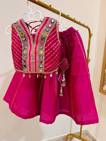 A bright magenta pink traditional lehenga/Chaniya choli set consisting of a heavily embroidered sleeveless vest and matching lehenga